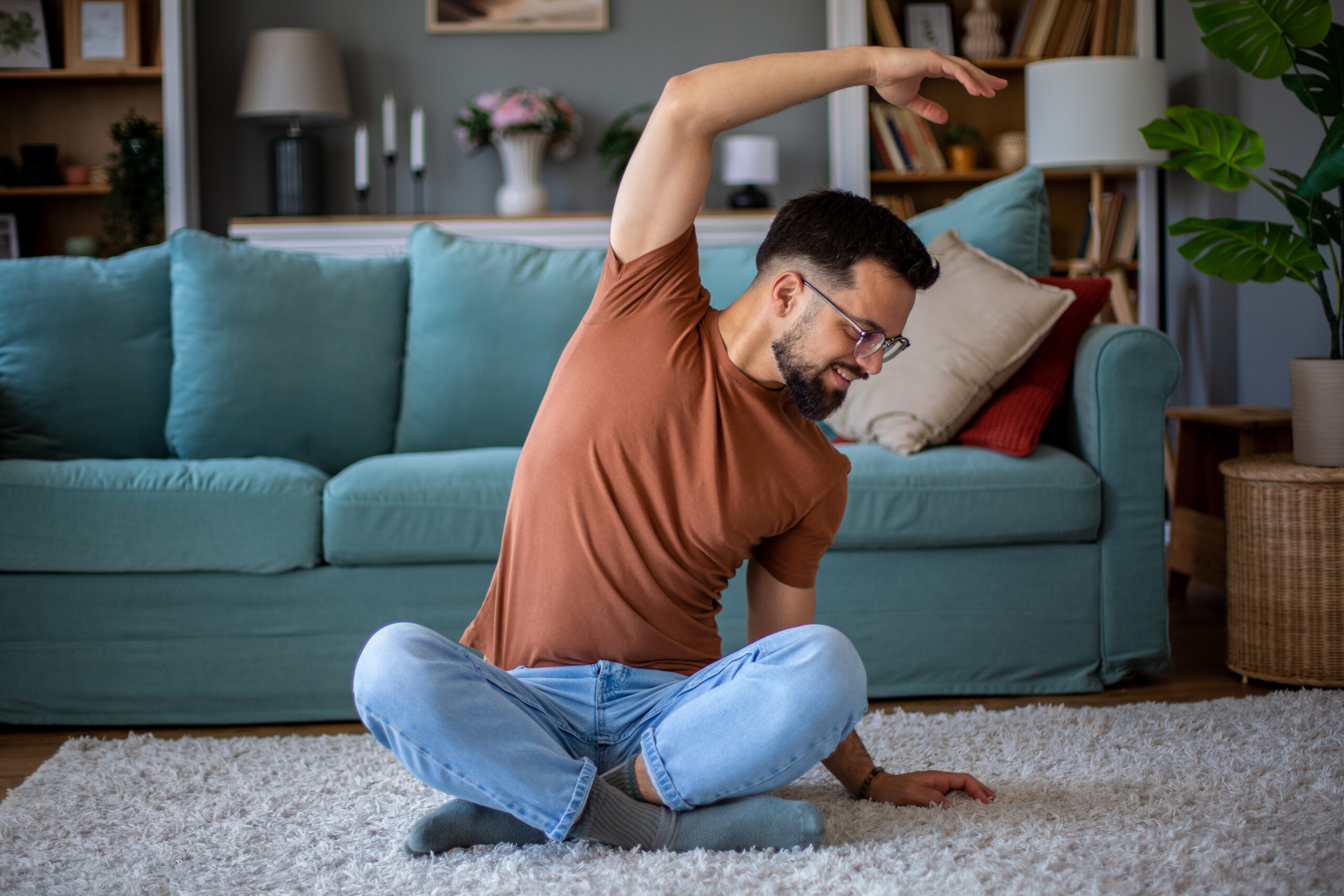 Young man doing stretching exercises at home in his living room