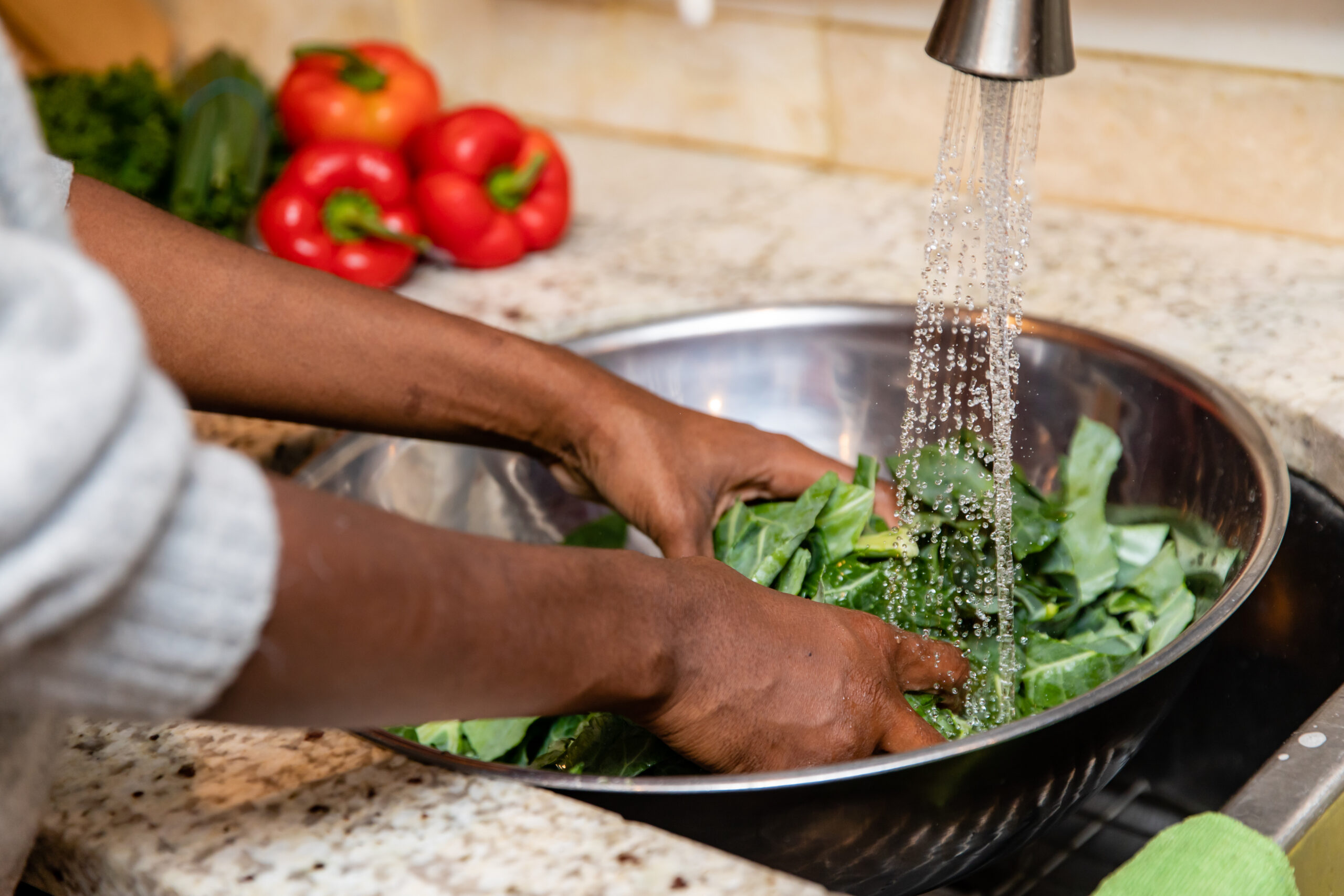 rinsing green leafy vegetables in the sink under running water